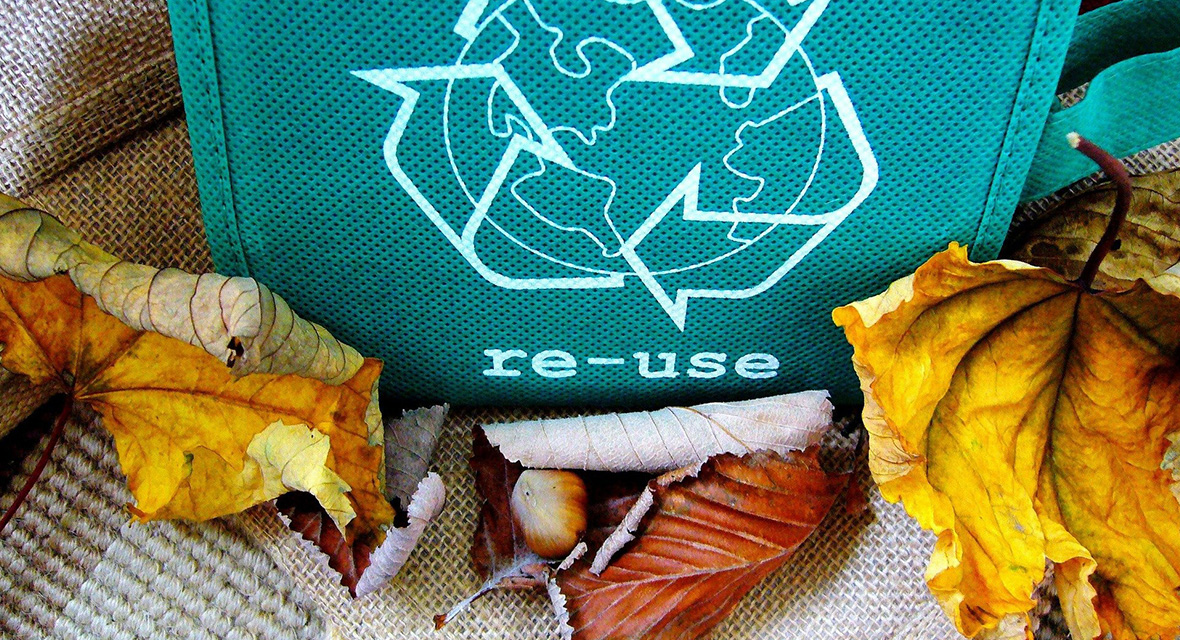 Un sac en toile avec le logo du recyclage et des feuilles mortes autour